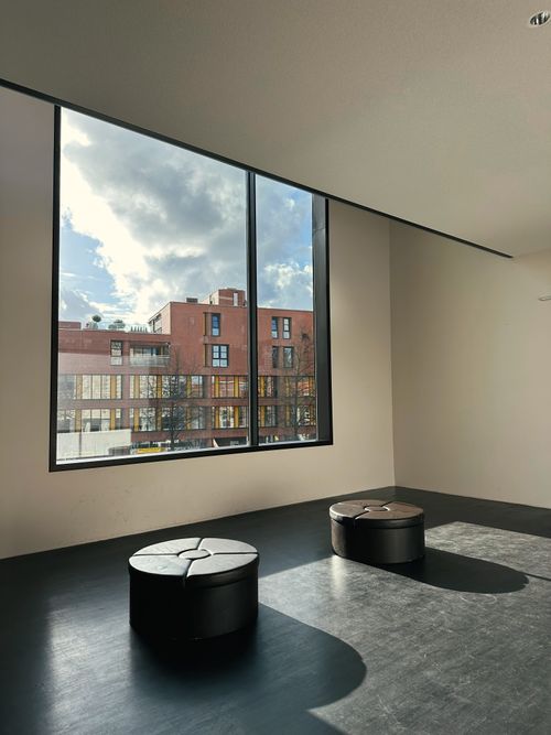 Free Spacious room with two stools and large window view of urban building under a cloudy sky. Stock Photo
