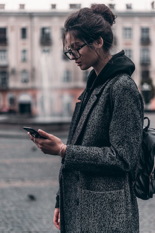 Mulher De Casaco Cinza E Preto Usando Smartphone