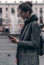 一位穿着外套的时尚年轻女子在城市户外使用智能手机