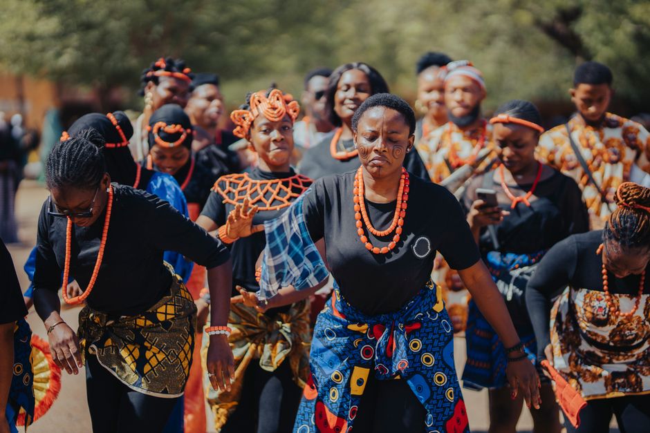 A group of people in traditional African attire performing a cultural dance outdoors.