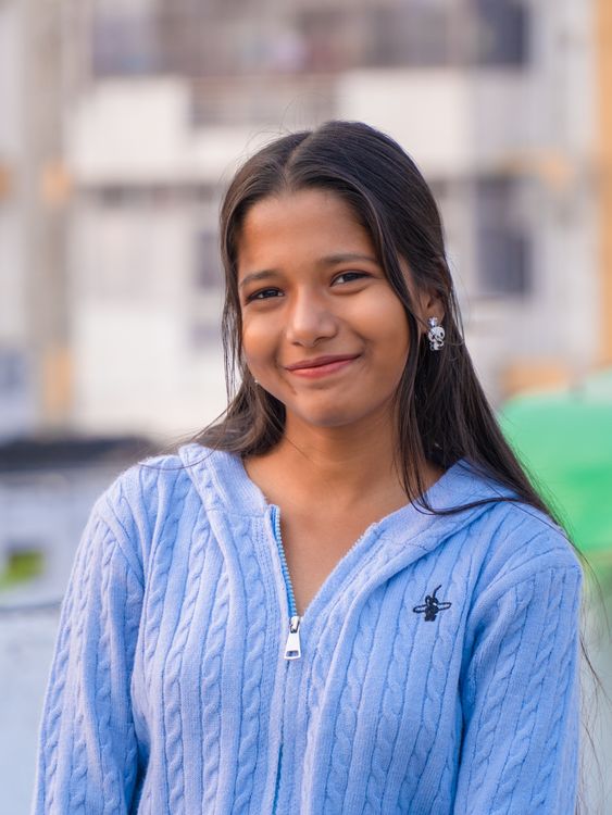 Young Woman Smiling Outdoors in Blue Sweater · Free Stock Photo