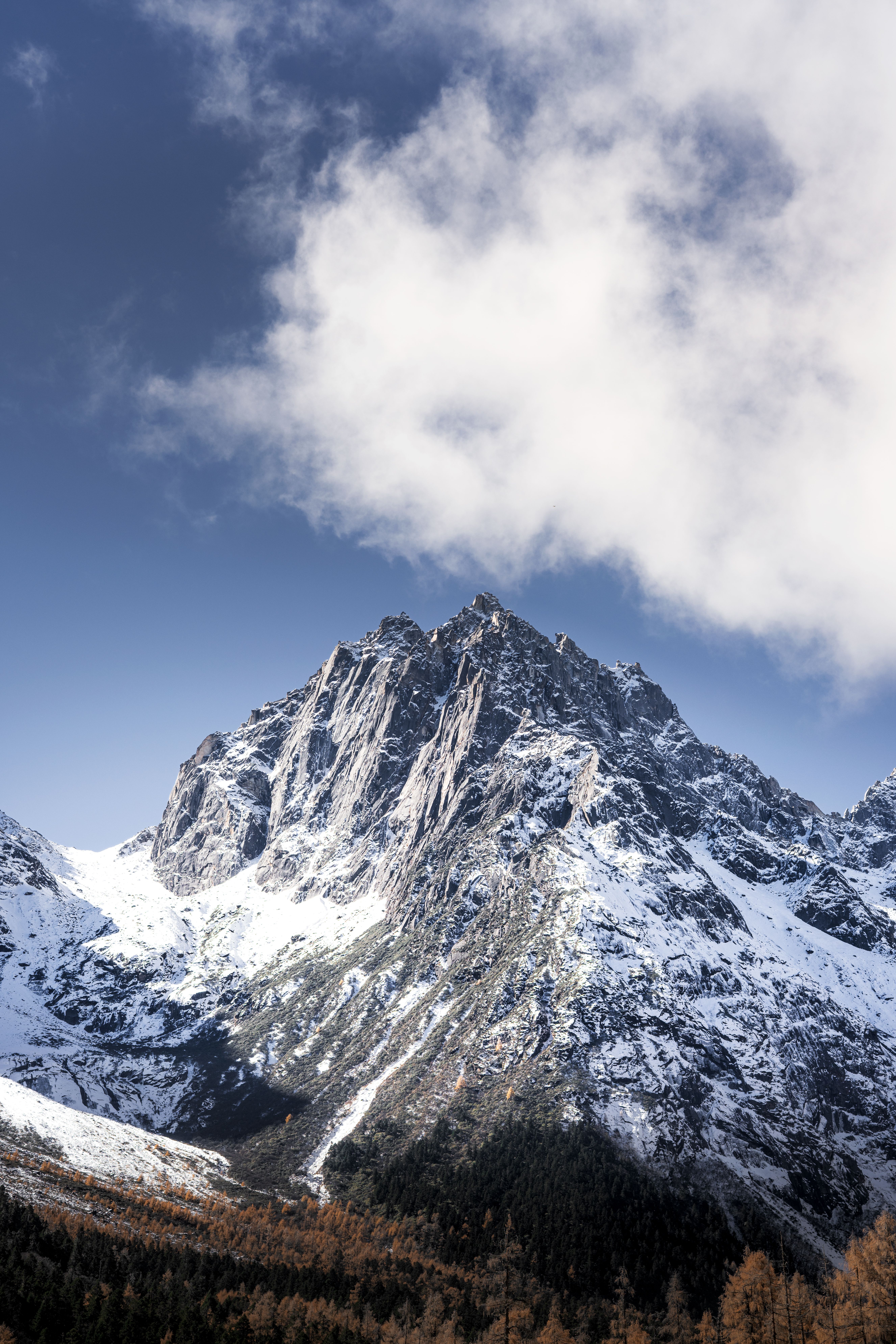 Breathtaking view of a snow-covered mountain peak under a clear blue sky in autumn.