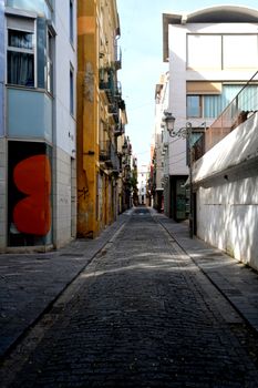 A picturesque narrow street with colorful buildings and cobblestones in a European city on a sunny day.
