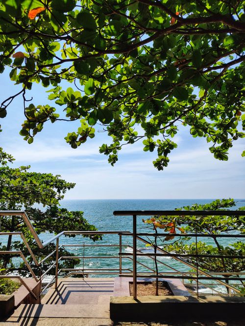Free Peaceful view of the ocean framed by greenery from a balcony in Thalassery, India. Stock Photo