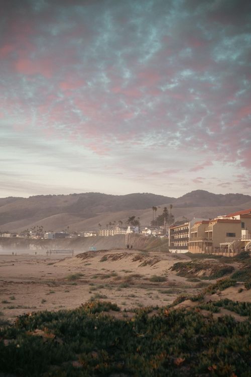 Free Serene evening view of Pismo Beach, California with colorful sunset skies and scenic hills. Stock Photo