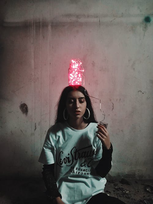 Woman in White and Black Crew Neck T-shirt With String Lights In A Bottle On Her Head