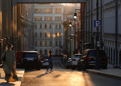 Free A serene city street at sunset with pedestrians and classic architecture. Stock Photo