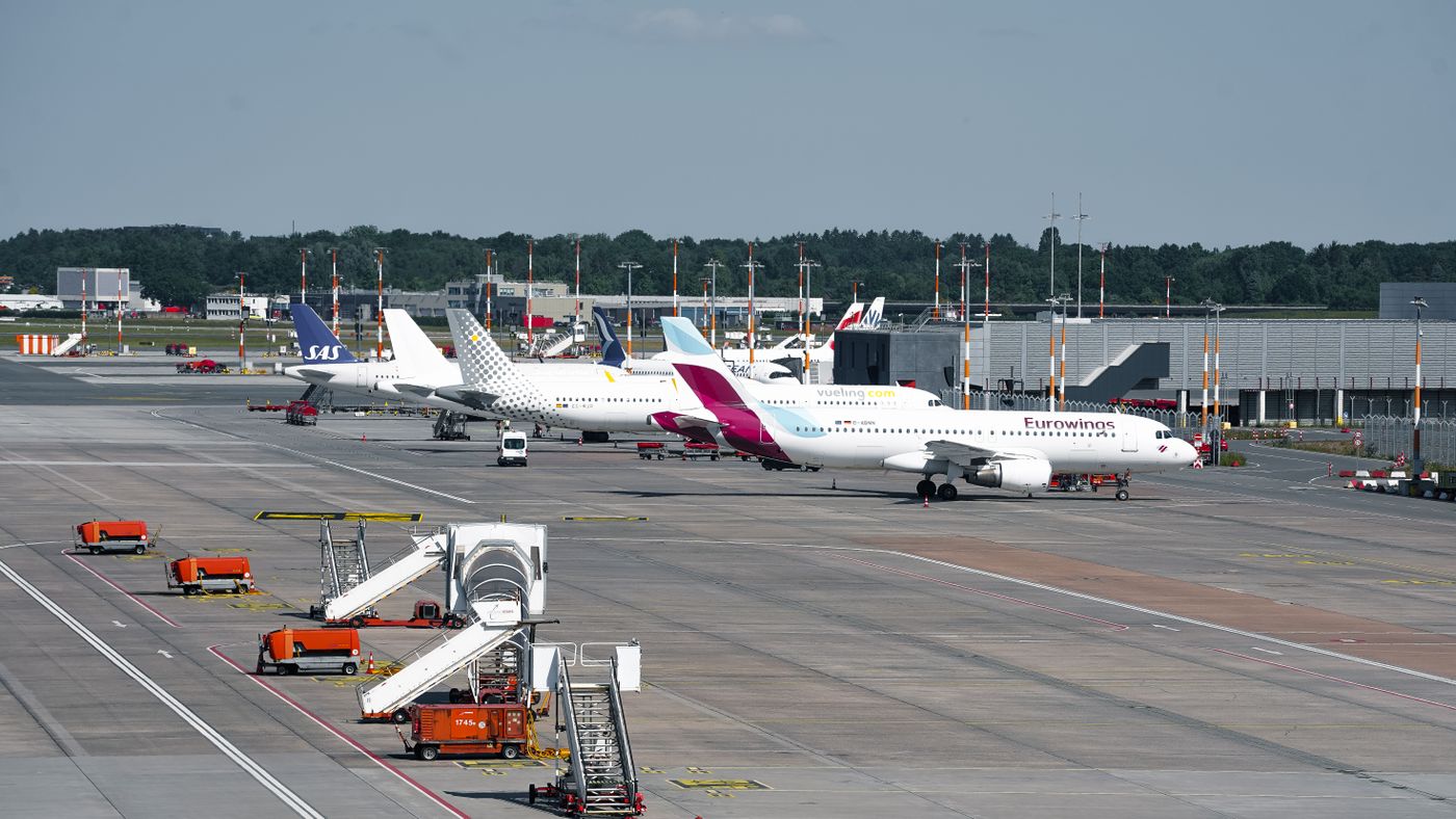 Several commercial aircraft parked at the terminal at Hamburg Airport during the day