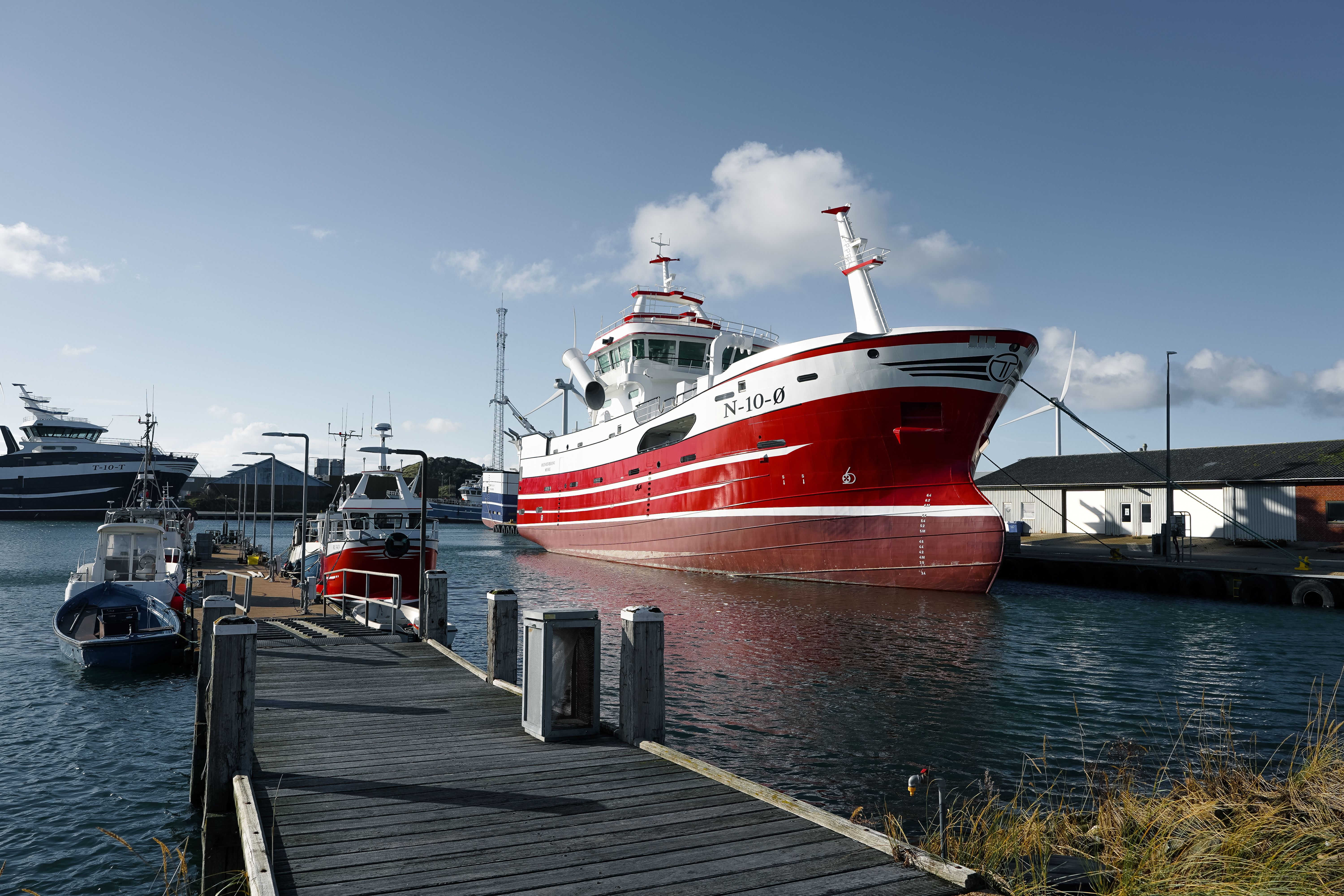 Idyllic scene of fishing boats moored in Hvide Sande harbor with a peaceful atmosphere.