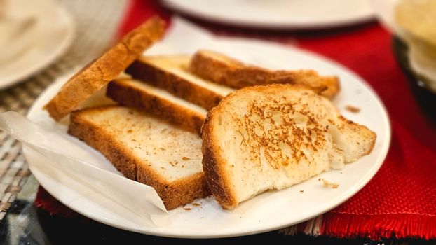 Appetizing close-up of toasted bread slices on a white plate indoors.