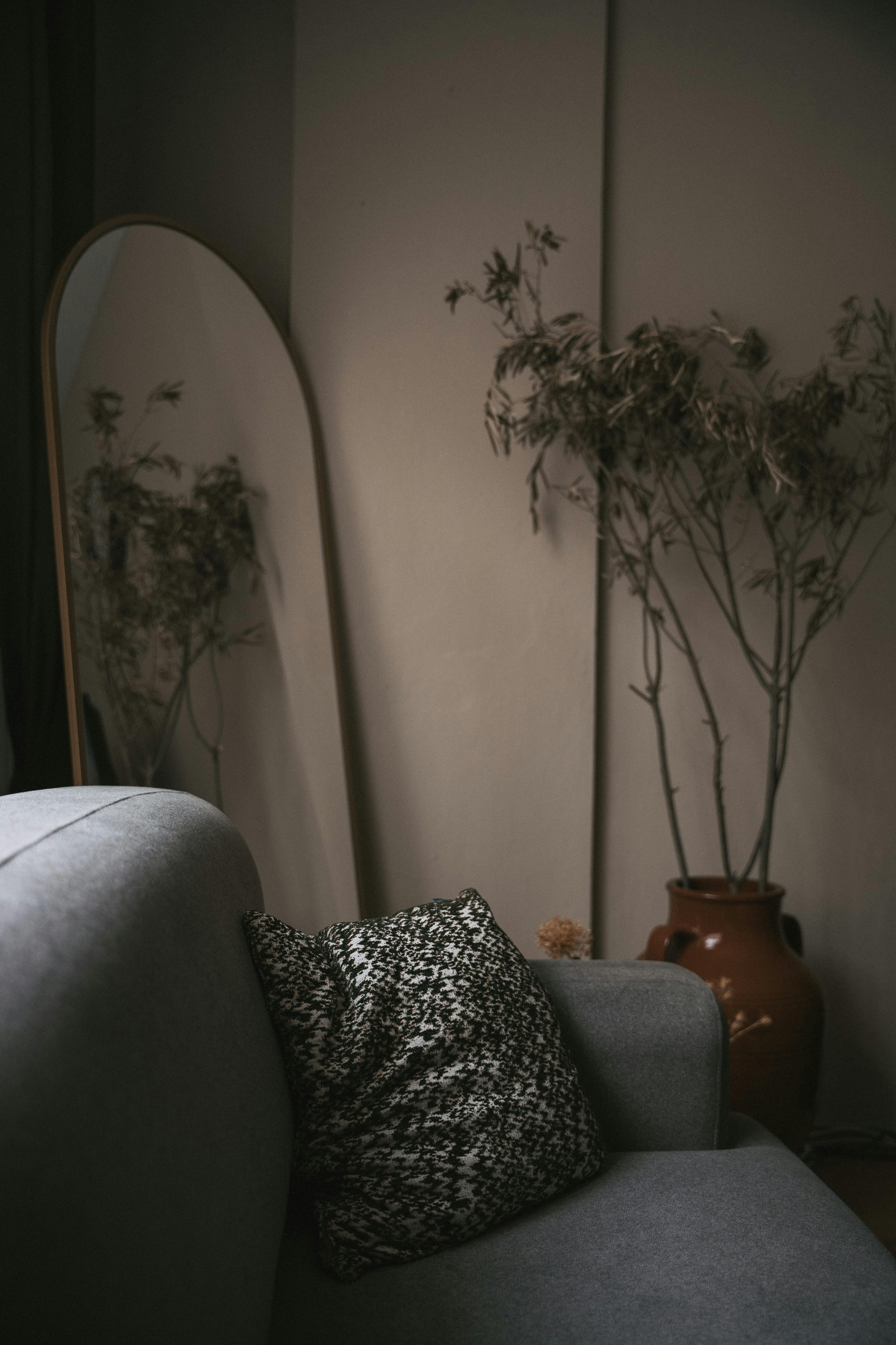 Elegant interior featuring a grey sofa, mirror, and dried plant in Istanbul, Turkey.