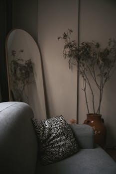 Elegant interior featuring a grey sofa, mirror, and dried plant in Istanbul, Turkey.