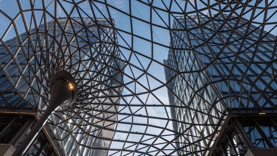 Dynamic view of a geometric glass dome structure in Hamburg's urban landscape.
