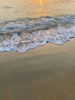 Calm sea waves gently kissing the sandy shore during a breathtaking sunset, exuding tranquility.