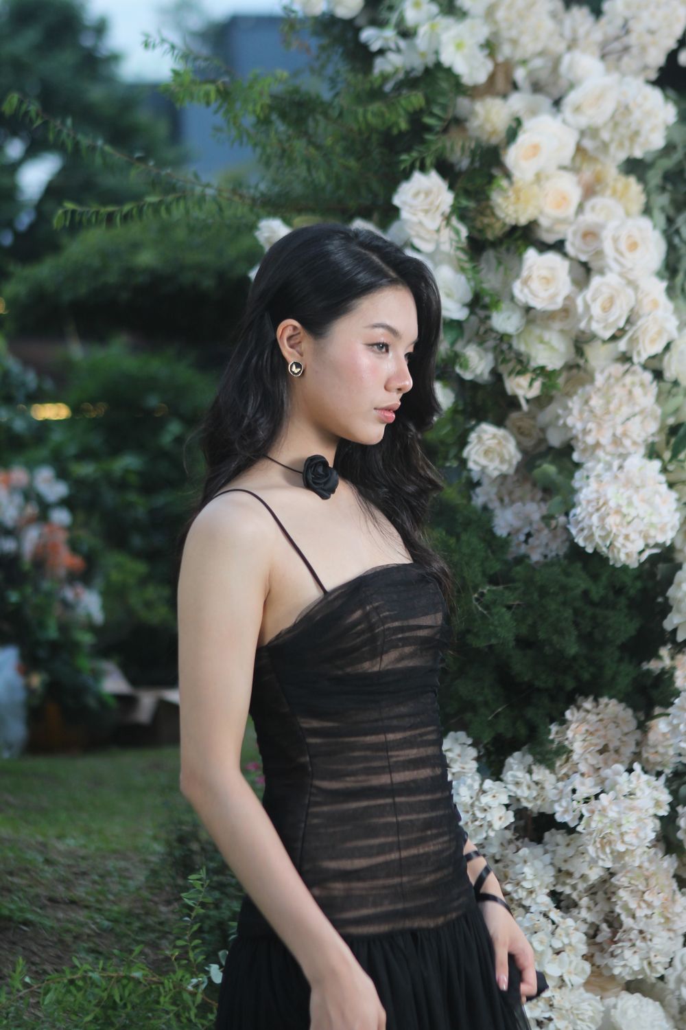 Elegant Woman in Black Dress with Floral Backdrop · Free Stock Photo
