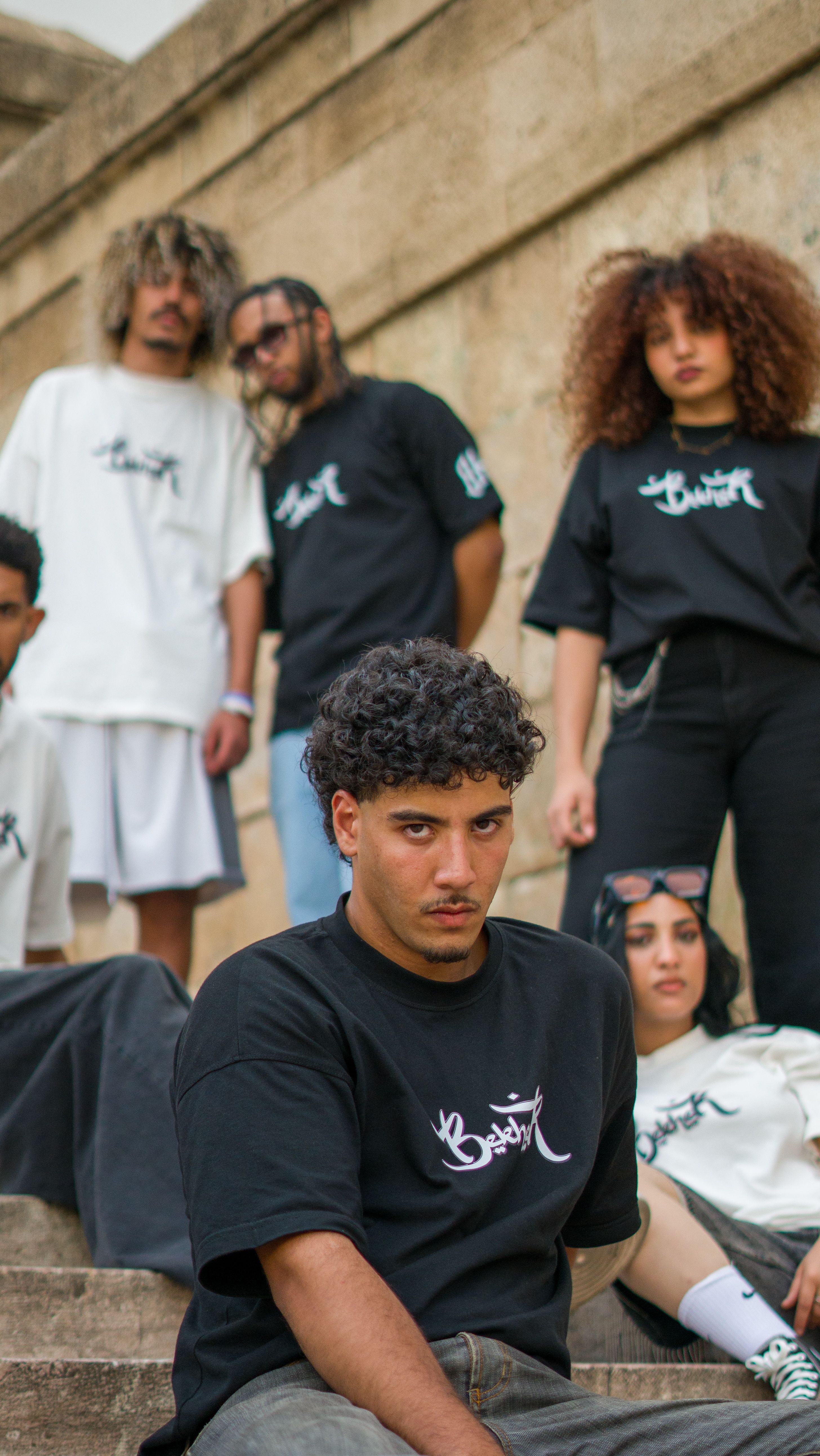 Jovens adultos estilosos com roupas urbanas de estilo streetwear posam em degraus de pedra no Marrocos.