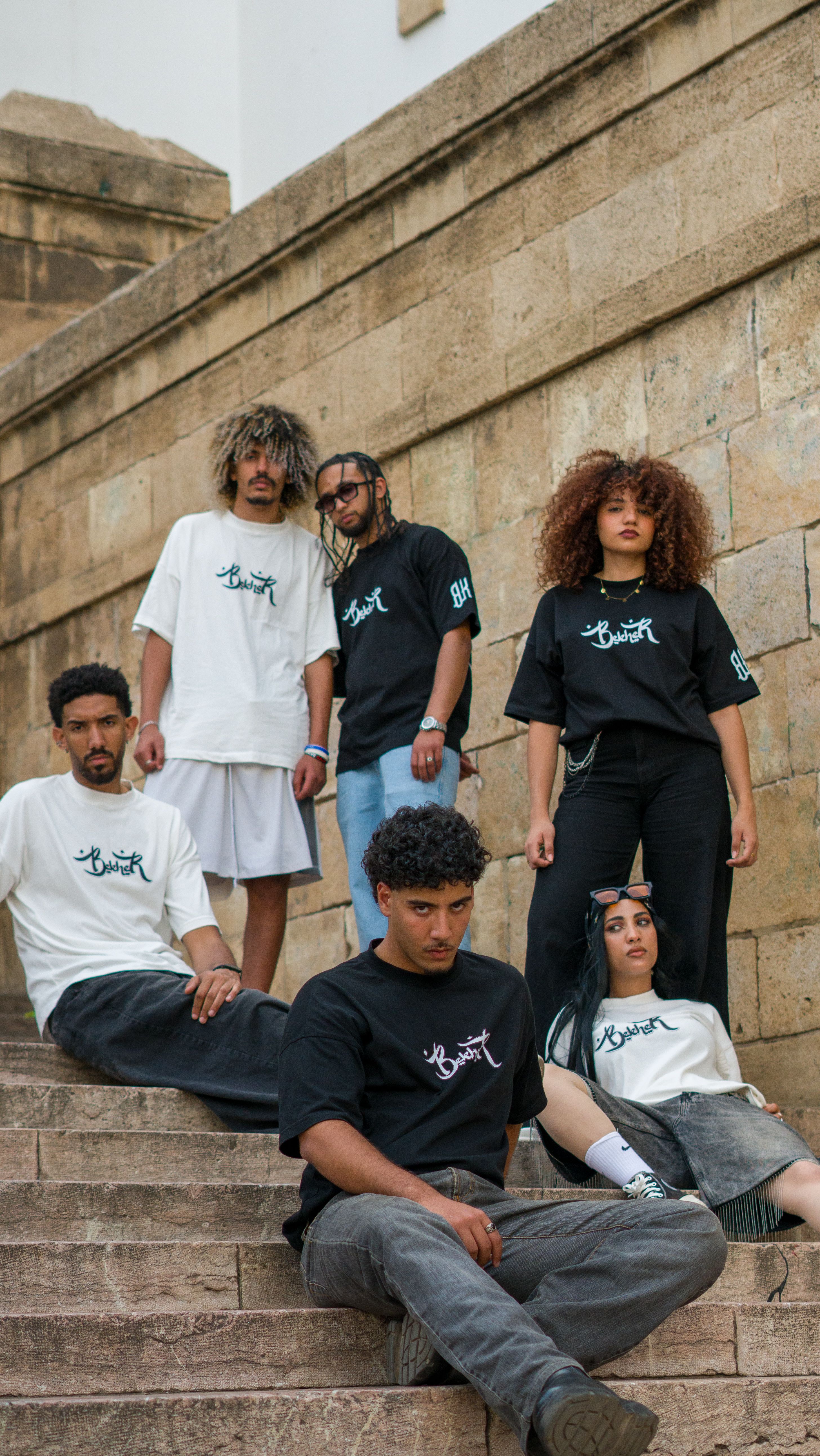 A stylish group of young adults showcasing urban streetwear on stone steps in Morocco.
