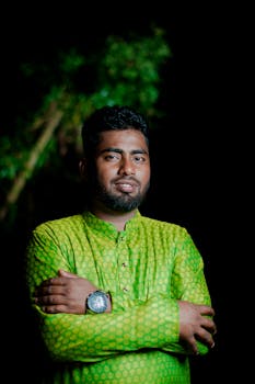 Portrait of a man in a green traditional outfit standing outdoors at night.