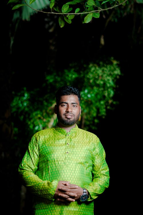 Free Portrait of a man in a bright green traditional outfit standing outdoors at night. Stock Photo