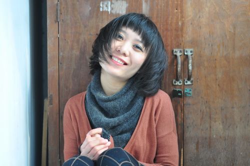 Free A cheerful woman in casual knitwear sits joyfully indoors. Stock Photo