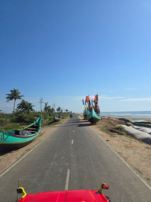 Free Scenic view of a coastal road lined with fishing boats under a clear blue sky. Stock Photo