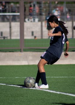 Young female soccer player controlling the ball on a sunny outdoor field.