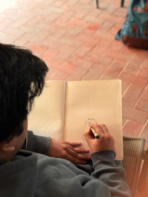 Free A person sketching in a notebook on a brick patio with a backpack nearby. Stock Photo
