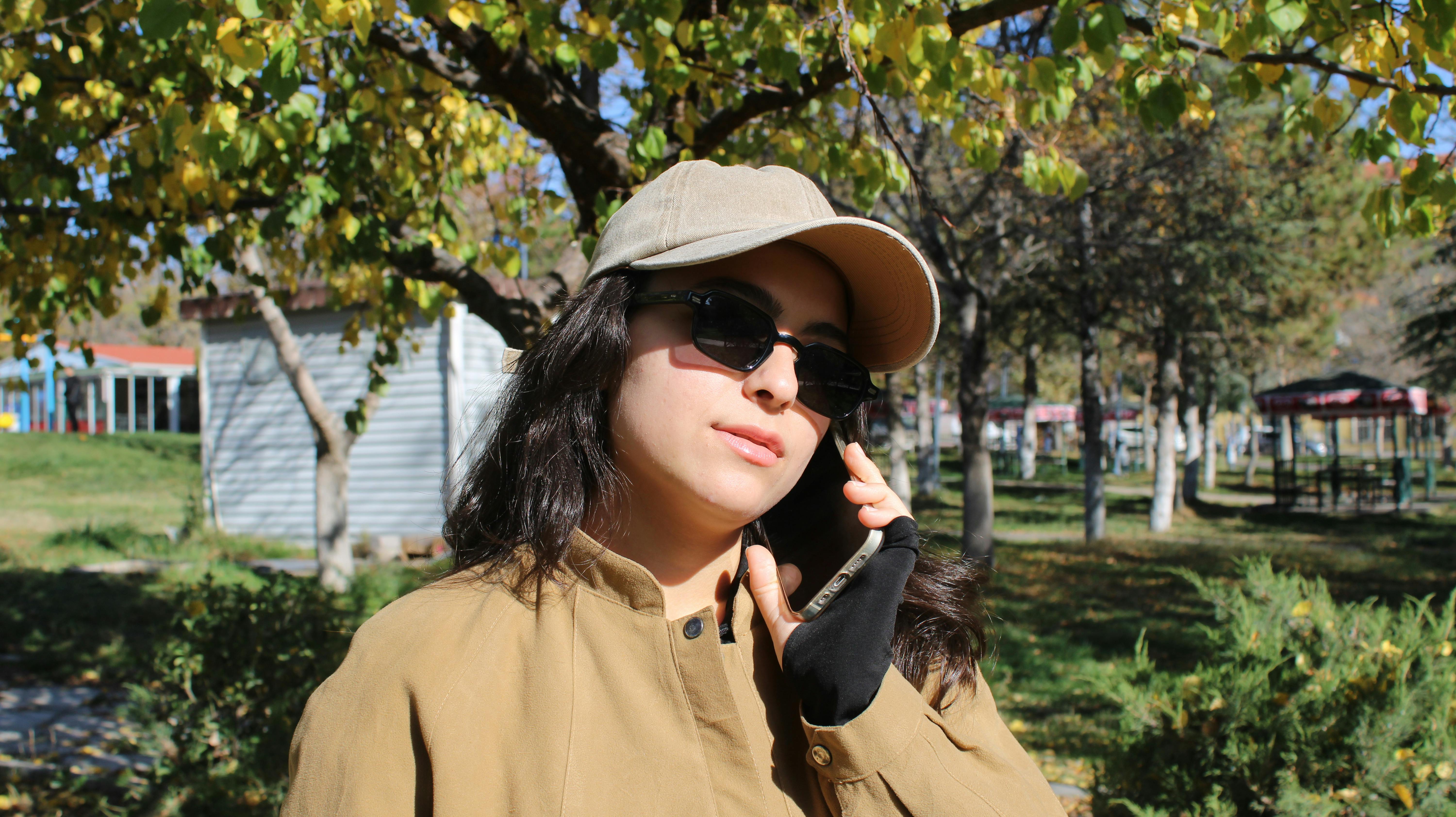 grátis Jovem mulher falando ao telefone enquanto aproveita um dia ensolarado no parque. Foto profissional