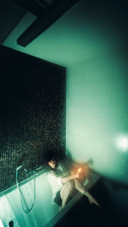 Free A person relaxing in a bathtub in dim, moody lighting with a sense of solitude. Stock Photo