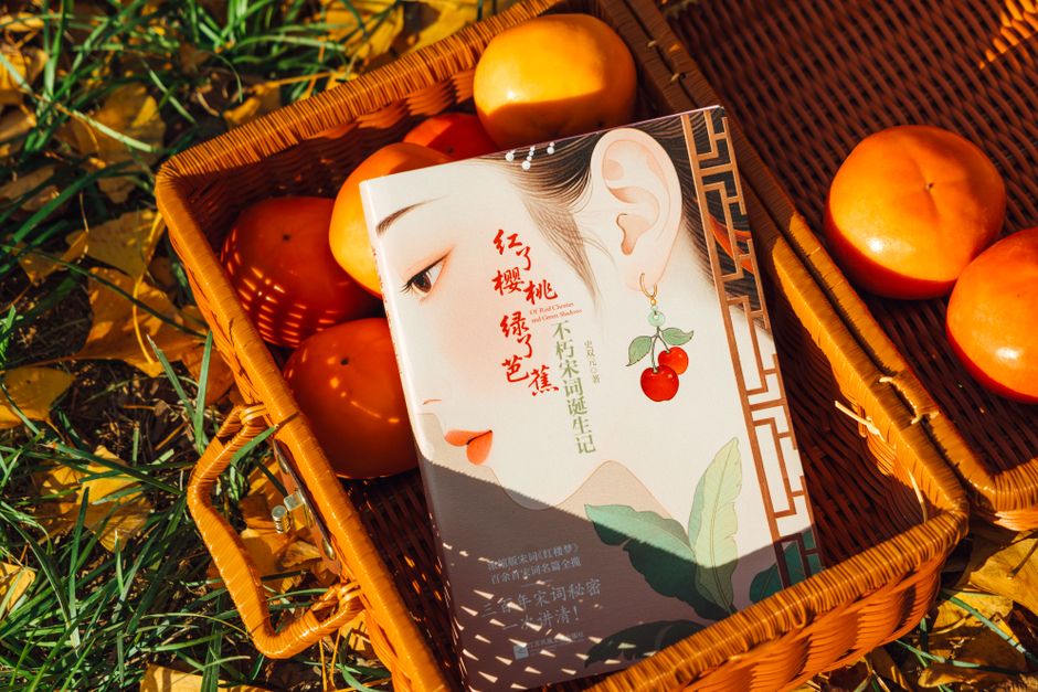 A beautifully designed book cover rests in a basket with ripe persimmons, surrounded by autumn leaves.