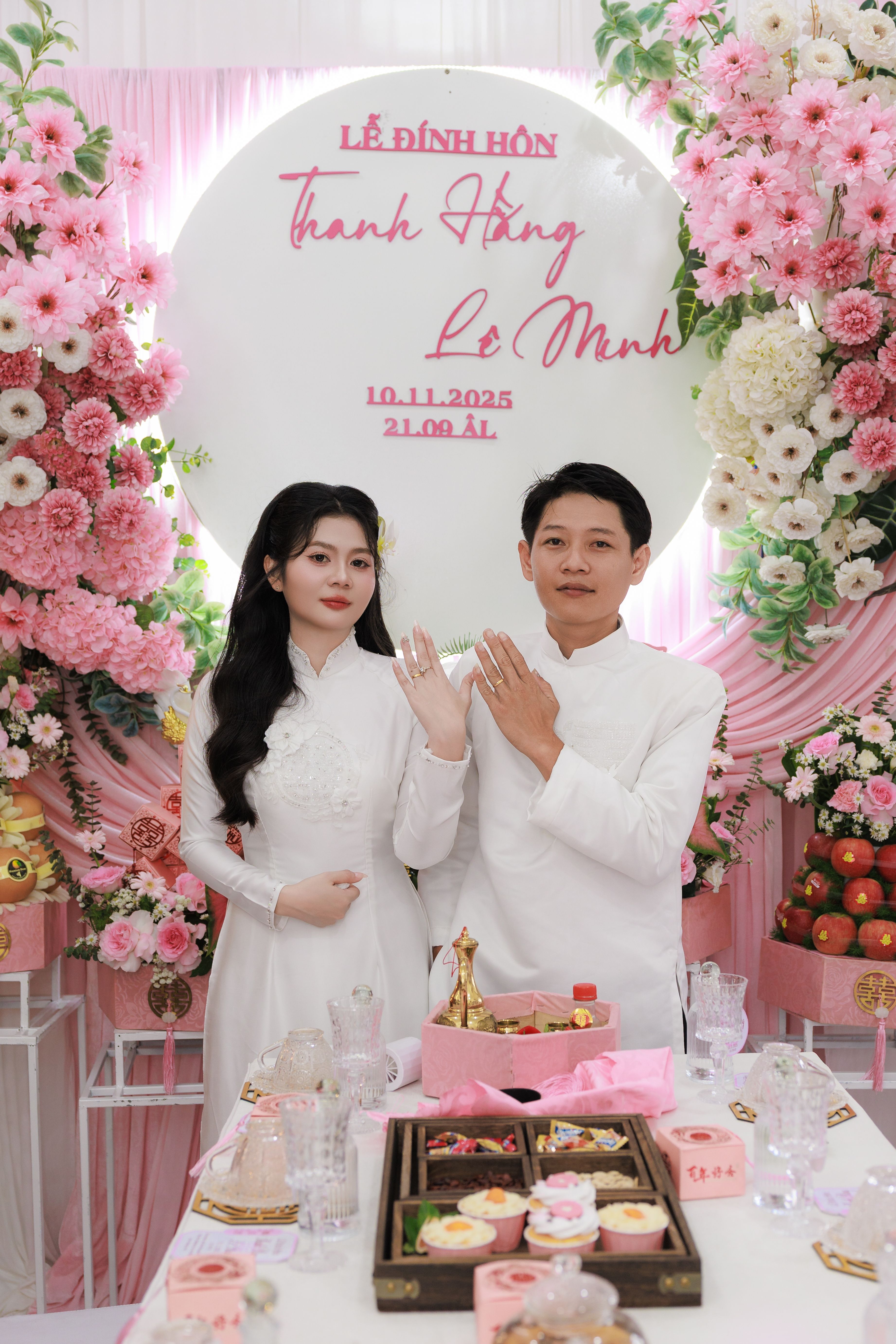 Elegant engagement celebration with couple in white, surrounded by floral decor and traditional elements.