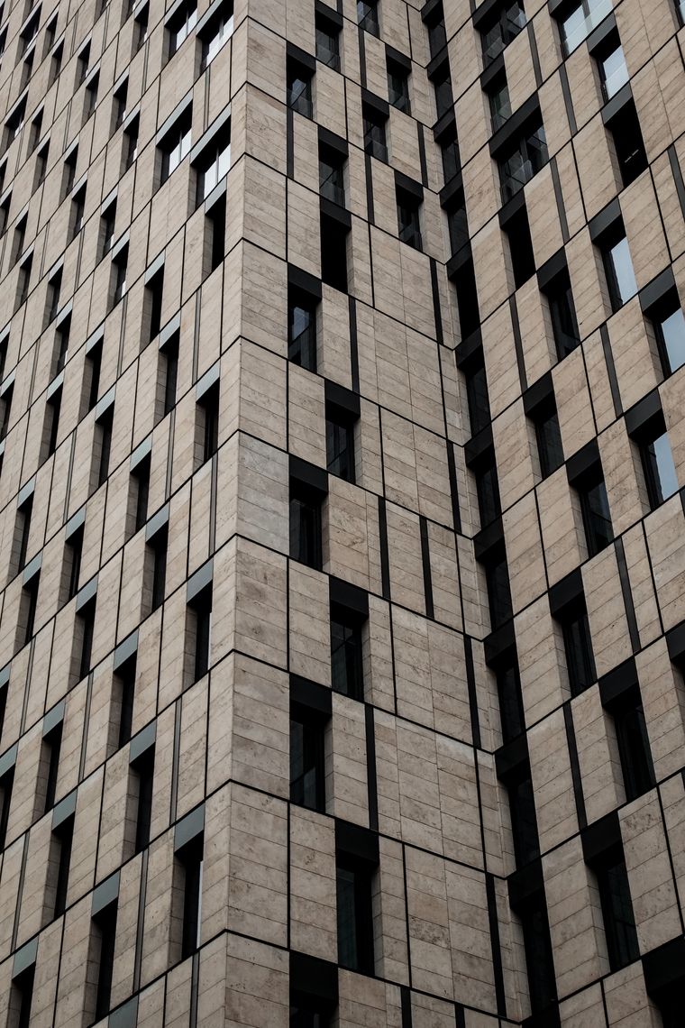 Modern stone-clad building facade with strong geometric shadow lines