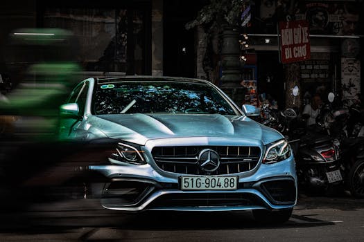 Front view of a silver luxury car parked on a bustling urban street with blurred motion.