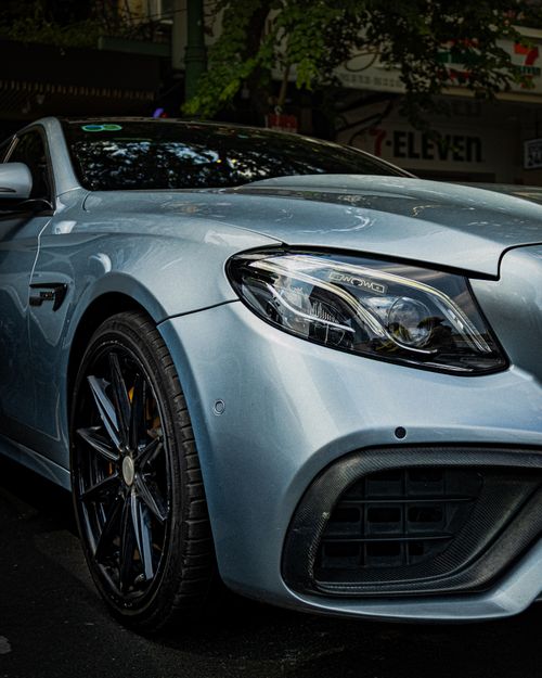 Free A sleek, silver luxury sedan parked in a city street near a 7-Eleven store. Stock Photo