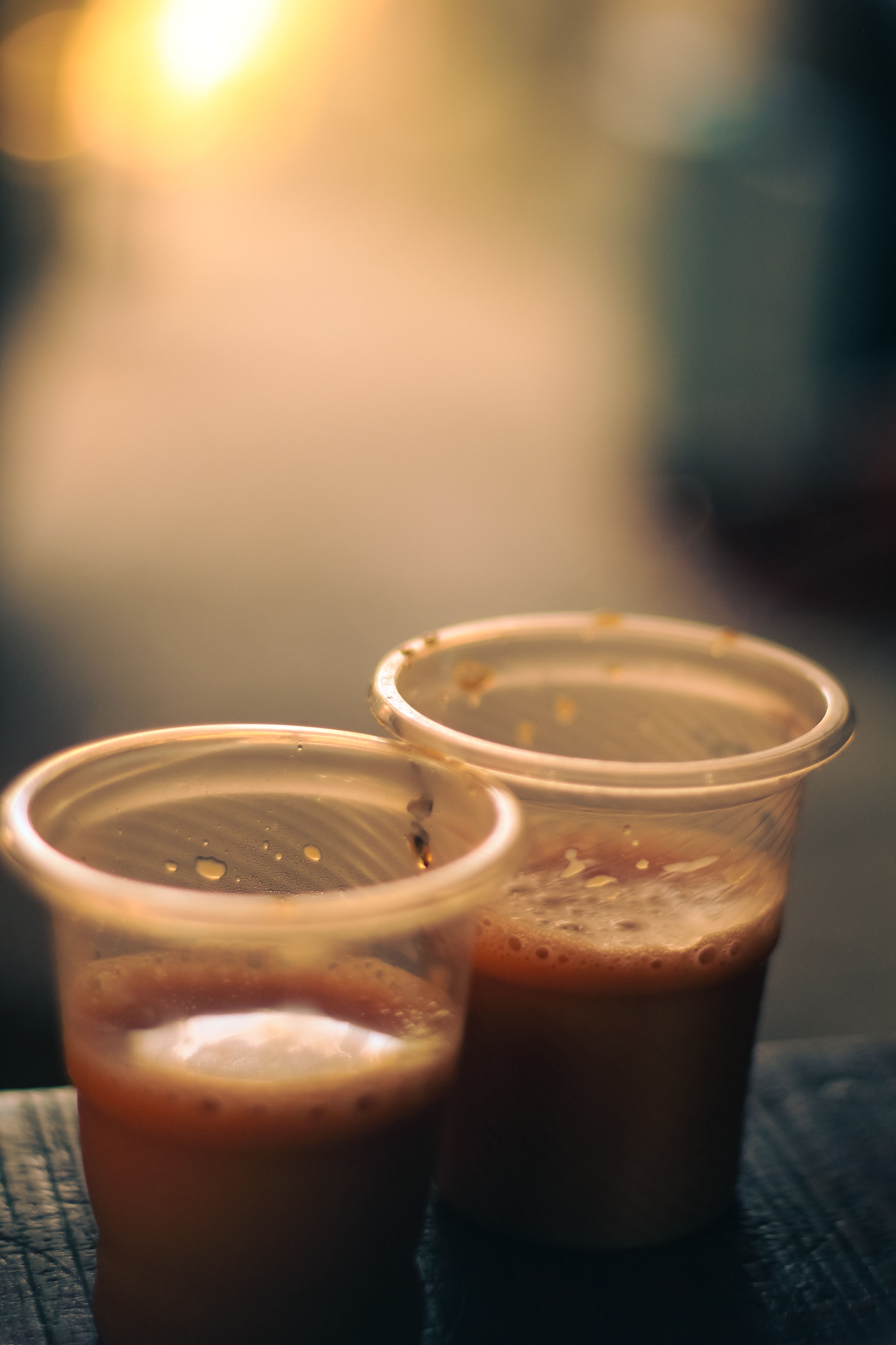 Plastic cups of traditional milk tea captured in warm evening light in Dhaka, Bangladesh.