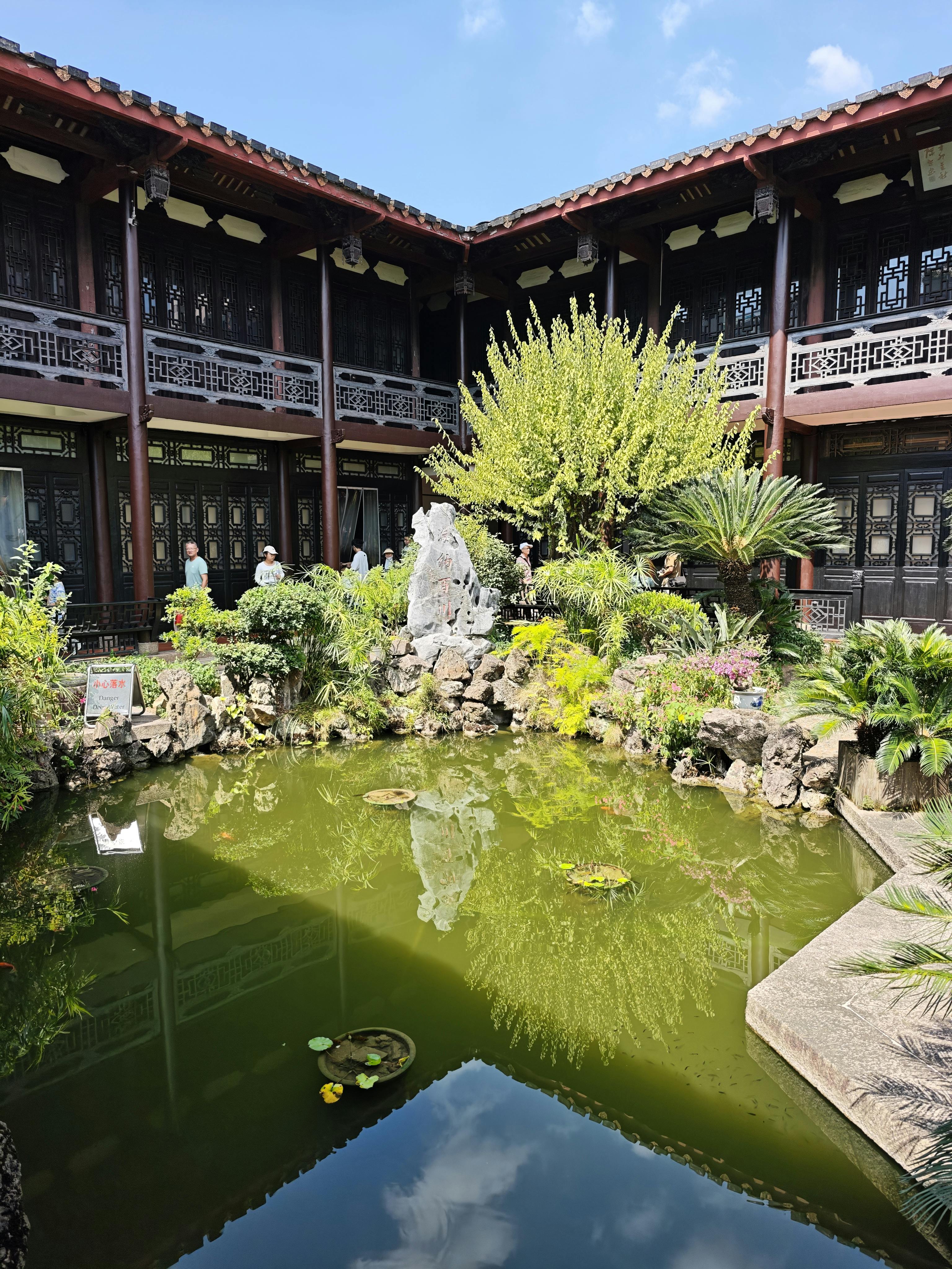 静谧的中式传统园林庭院，池塘与葱郁绿植相映，唤起中华人民共和国广州市广东省中医院疗愈花园般的氛围