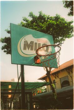 Rustic basketball hoop with Milo advertisement outdoors, under clear sky.