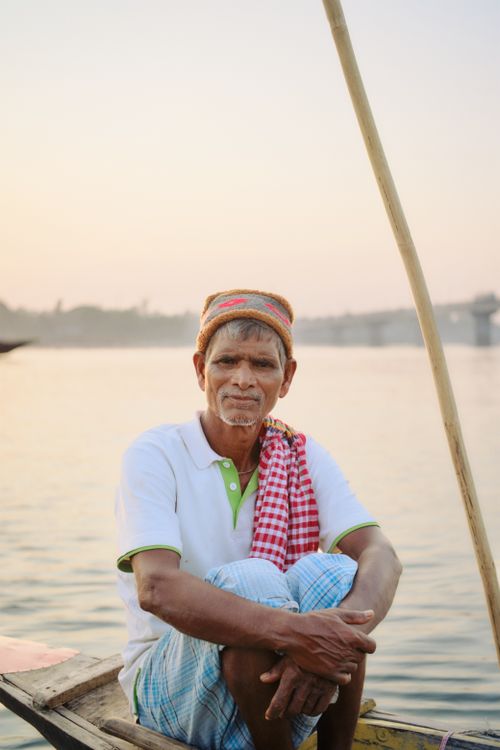 Free Portrait of an elderly fisherman sitting on a boat at sunset on a river in Bangladesh. Stock Photo