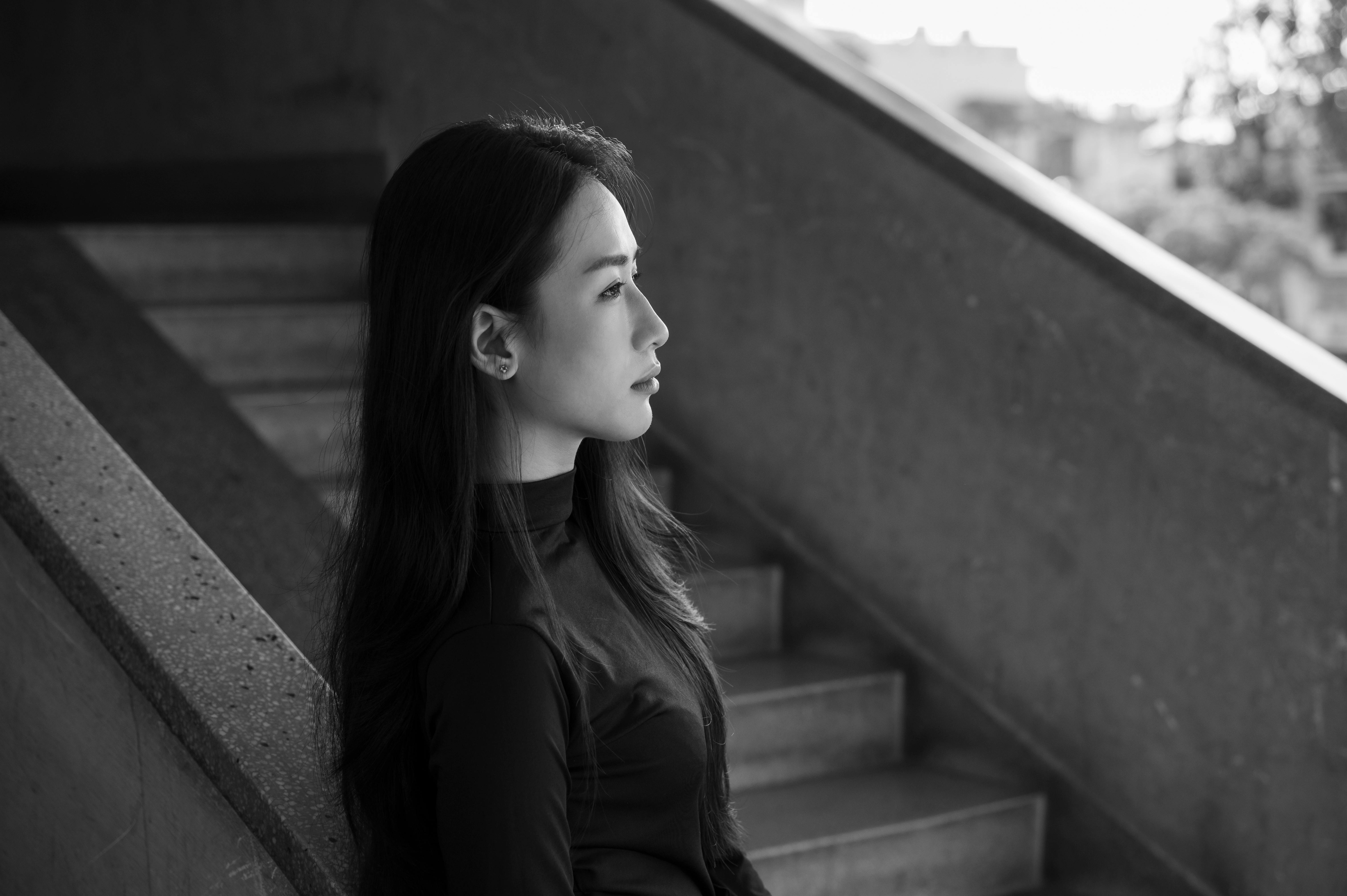 階段に座っている横顔の女性の白黒ポートレート。