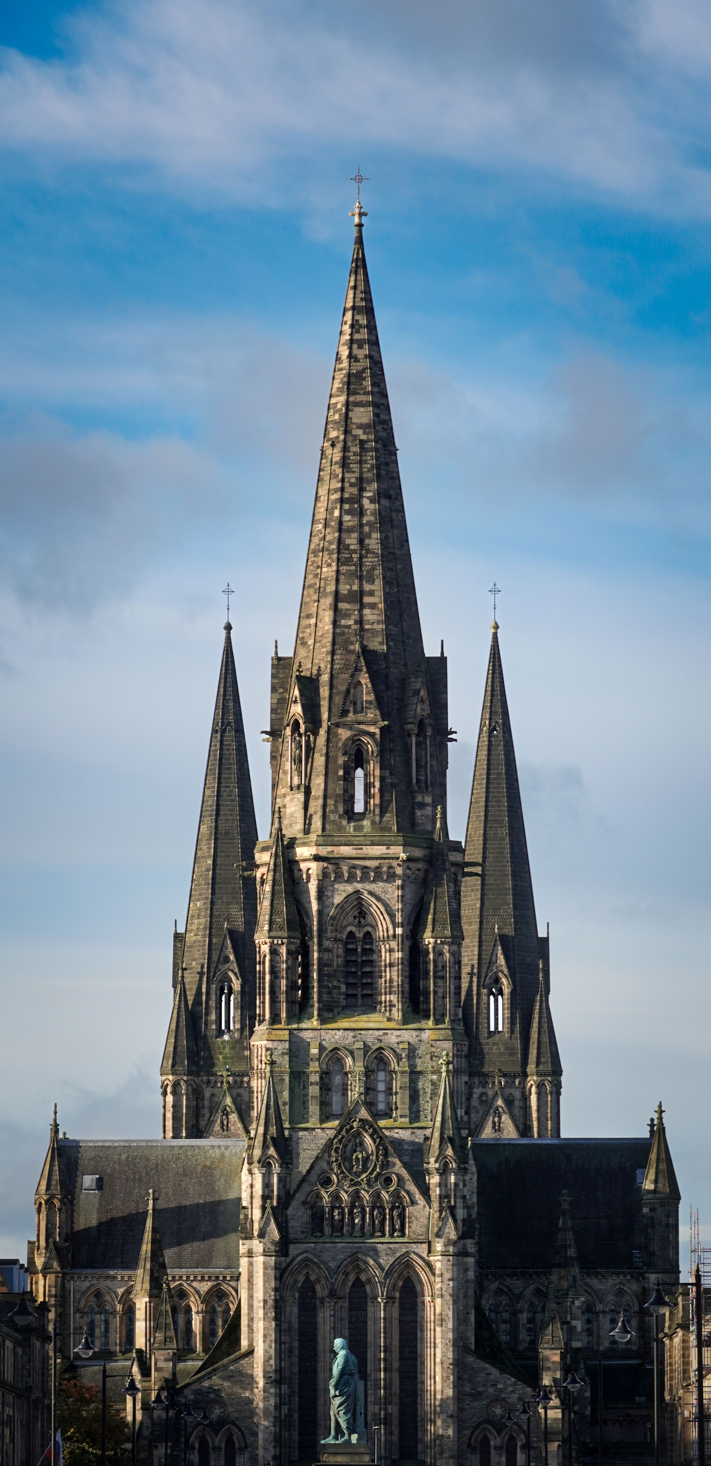 Stunning view of a Gothic cathedral in Scotland, showcasing its dramatic spires against a vibrant sky.