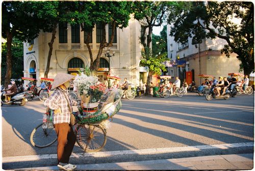 Free Traditional Vietnamese street vendor with flowers in bustling Hanoi intersection. Stock Photo