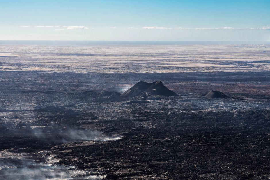 Breathtaking Epic ATV & Helicopter Combo Adventure in Reykjavik Review Review 2026 - A wide aerial view of a rugged volcanic landscape with visible lava flows and smoke rising from the surface.