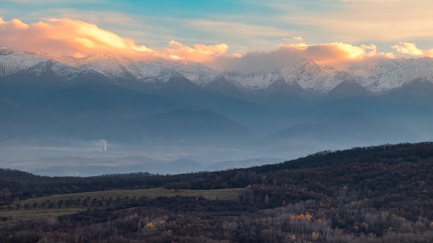 Captivating view of snowy mountains under a dramatic sunrise sky, perfect for nature lovers.