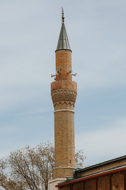 Free A tall, historic minaret tower stands prominently against a clear blue sky, showcasing Islamic architecture. Stock Photo