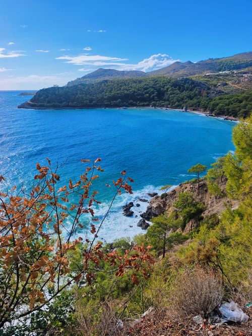 Free Scenic view of a vibrant blue bay with rocky cliffs and lush greenery. Stock Photo
