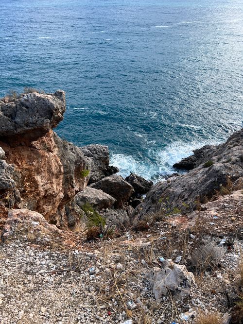 Free A stunning view of rugged cliffs and calm ocean waves beneath the clear sky. Stock Photo