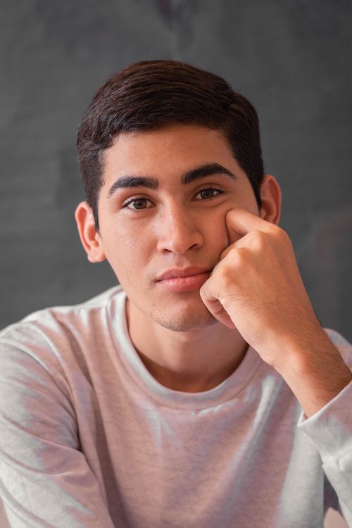 Free Close-up portrait of a young man posing indoors with a thoughtful expression. Stock Photo