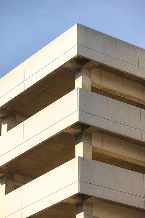 Free Close-up of the corner of a minimalist concrete building under a clear blue sky, captured in sunlight. Stock Photo
