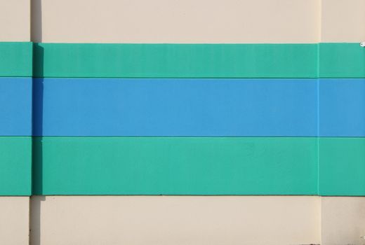 Abstract image of a wall with teal and blue horizontal stripes on a beige background.