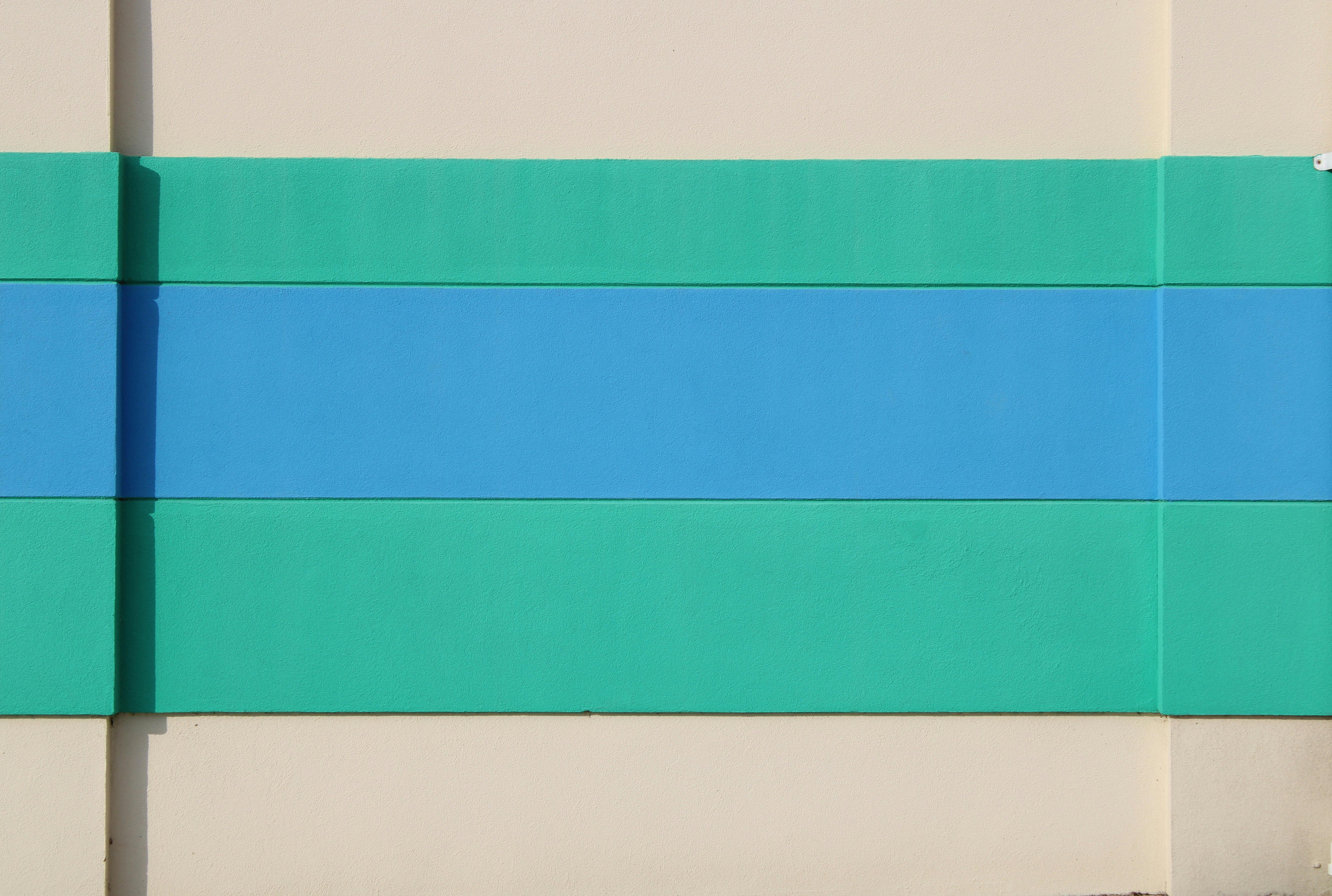 grátis Imagem abstrata de uma parede com listras horizontais em tons de verde-azulado e azul sobre um fundo bege. Foto profissional